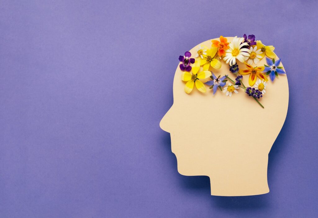 World mental health day concept. Human head symbol and flowers on a violet background